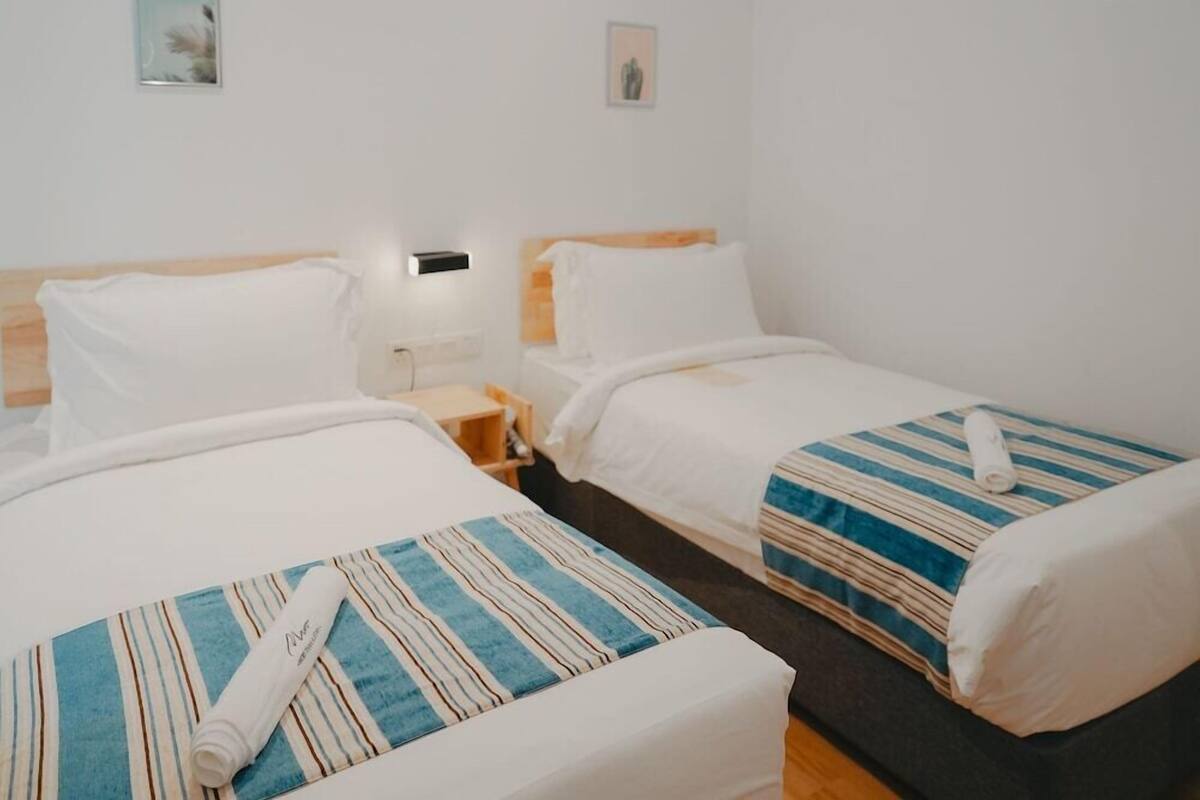 Een hotelkamer met twee bedden, elk met een gestreepte deken en een opgerolde handdoek.