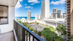 Un balcon offrant une vue sur le paysage urbain, avec de grands immeubles et un parking.