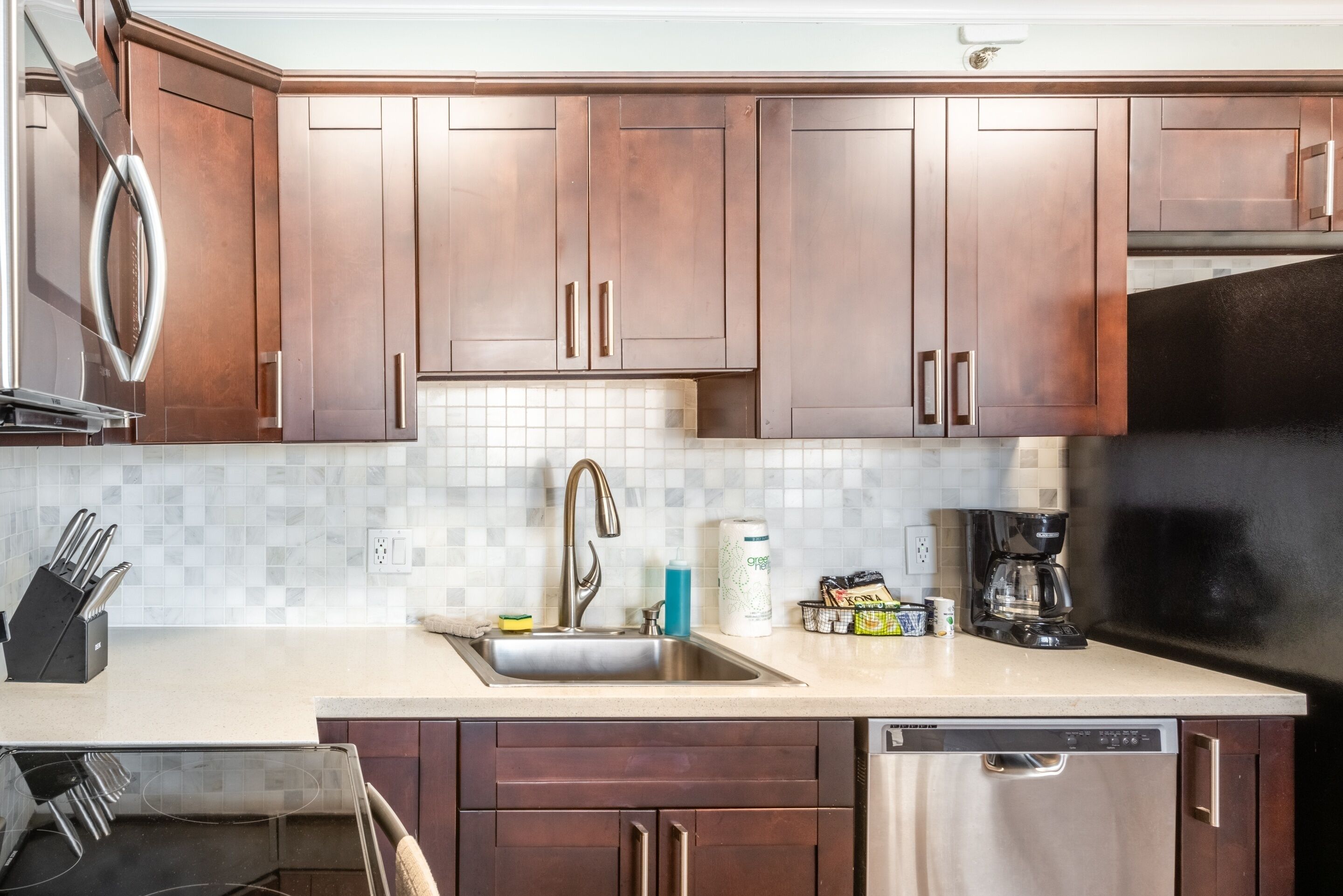 A kitchen with wooden cabinets, a stainless steel sink, a coffee maker, and a dishwasher.