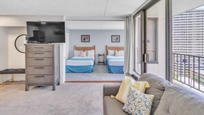 Une chambre d’hôtel avec un canapé, deux lits, une commode et un téléviseur.