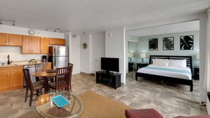 A modern hotel room with a kitchen area, a dining table, and a bed with a view. - Deluxe Ocean View Condo on 31st Floor - Free Parking & Wifi! (Honolulu)