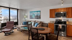 A modern apartment with a balcony, a dining area, a kitchen with stainless steel appliances, and a city view. - Deluxe Ocean View Condo on 31st Floor - Free Parking & Wifi! (Honolulu)