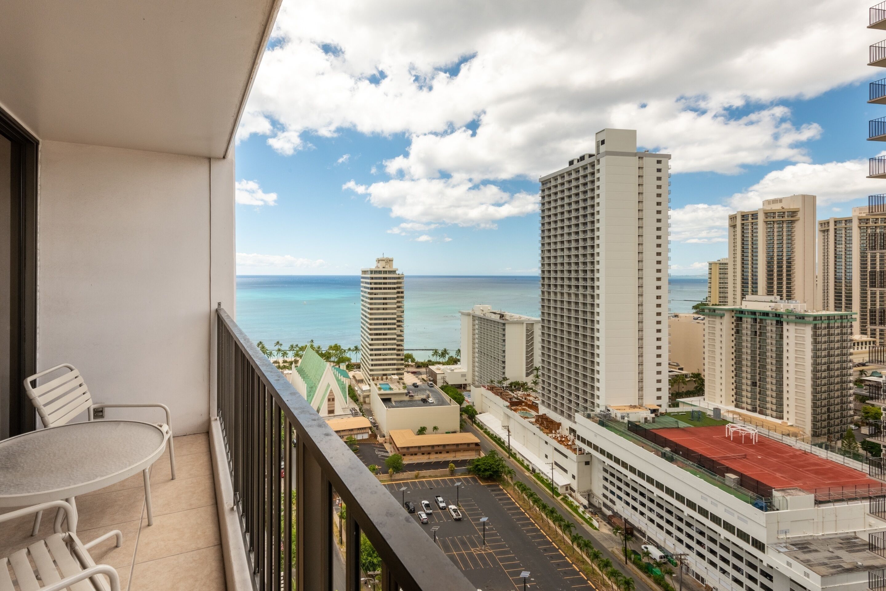 A balcony with a view of a cityscape and the ocean.