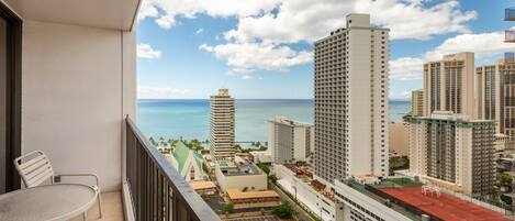 A balcony with a view of a cityscape and the ocean.