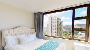 Ein Hotelzimmer mit einem großen Bett, Blick auf eine Stadtansicht und einem Vorhangfenster.