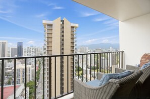 A balcony with a view of a cityscape, including high-rise buildings and a clear sky.