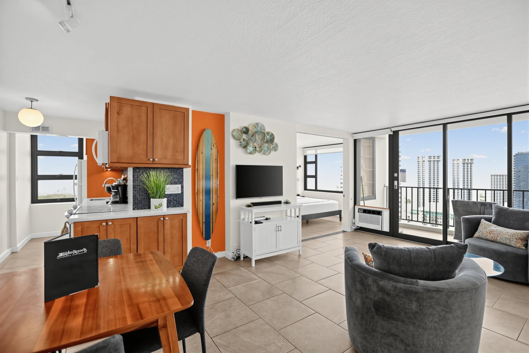A modern apartment with a kitchen, dining area, living room, and balcony with city views.
