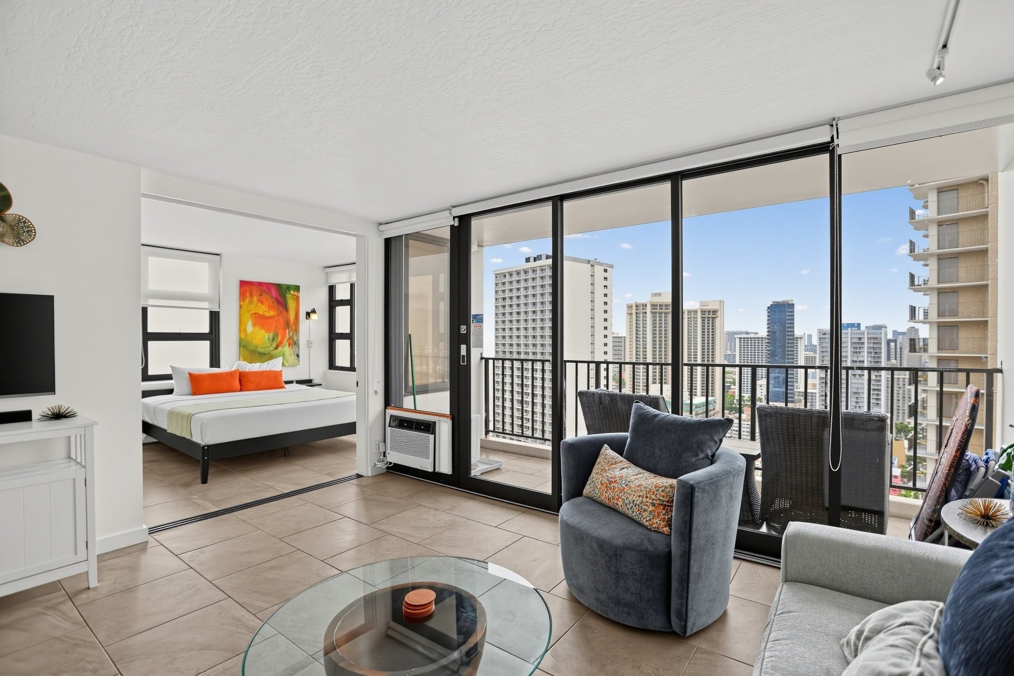A modern apartment with a balcony, a bed, a sofa, and a TV.