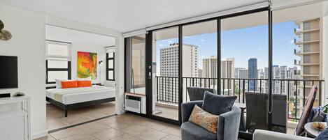 Un apartamento moderno con balcón, una cama, un sofá y un televisor.