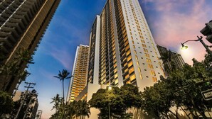 Un edificio alto con varios pisos, rodeado de árboles y farolas.