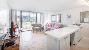 Un apartamento moderno con cocina, sofá, mesa de comedor y un amplio ventanal con vistas a la ciudad.