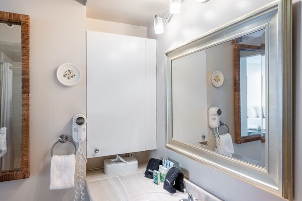 A bathroom with a large mirror, a towel rack, a hairdryer, and a sink.