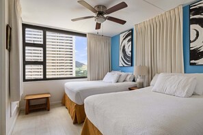 A hotel room with two beds, a ceiling fan, a window with blinds, a small wooden stool, and a painting on the wall. - Spacious 14th Floor Corner Suite, Partial Diamond Head and Ocean Views, FREE Parking! (Honolulu)