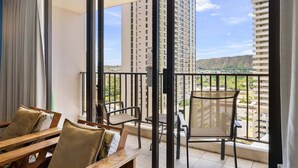 Ein Balkon mit Blick auf eine Stadtlandschaft, darunter hohe Gebäude und ein entfernter Gebirgszug.
