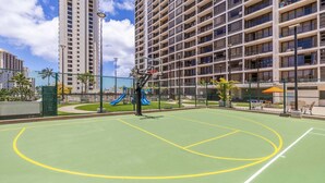 Ein Basketballplatz im Freien mit einer blauen Rutsche, umgeben von einem Hochhaus.