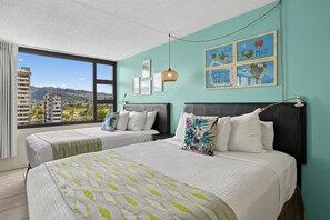 Ein Hotelzimmer mit zwei Betten, einem großen Fenster mit Stadtblick und Kunstwerken an den Wänden.