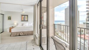 A bedroom with a bed, bedside table, and a view of the ocean and buildings. - High Rise Ocean View Waikiki Condo, FREE Parking & Wi-Fi (Honolulu)