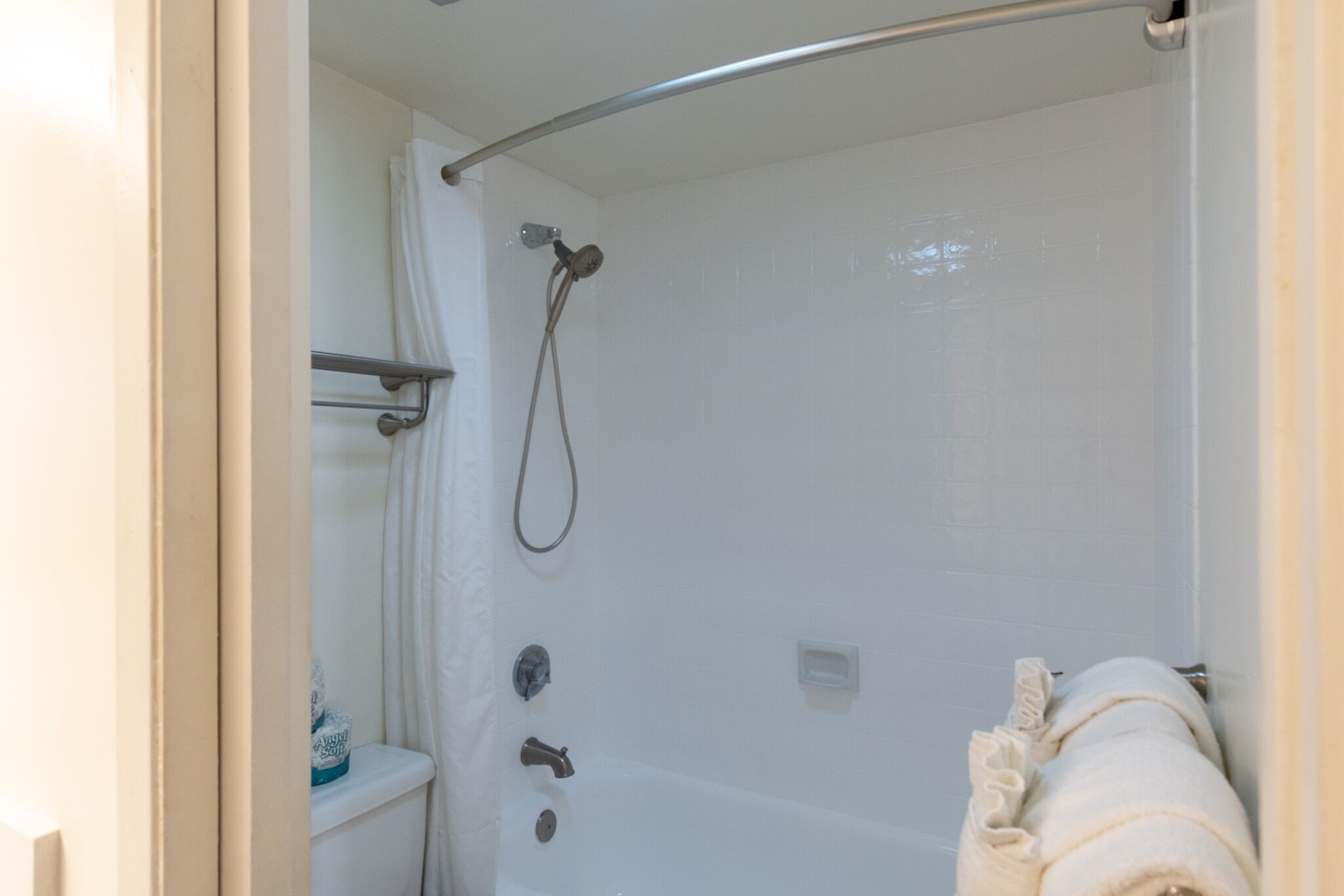 A bathroom with a shower, toilet, and towel rack.