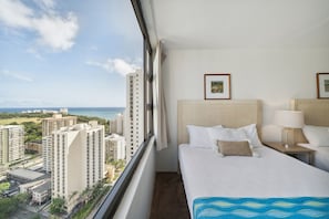 Ett hotellrum med ett stort fönster som erbjuder utsikt över staden och havet.