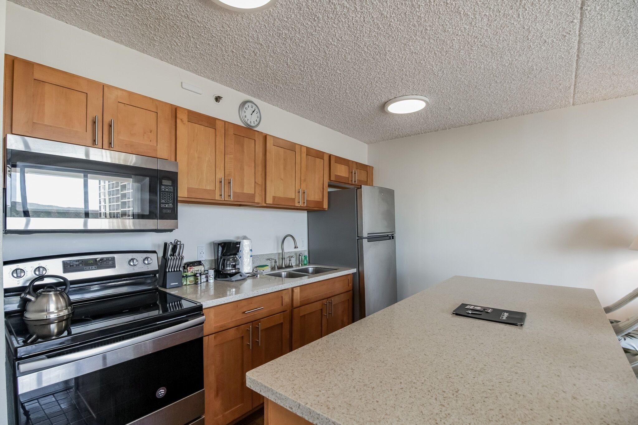 A modern kitchen with wooden cabinets, stainless steel appliances, and a granite countertop.
