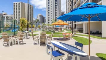 A courtyard with outdoor seating, a playground, and tall buildings in the background.