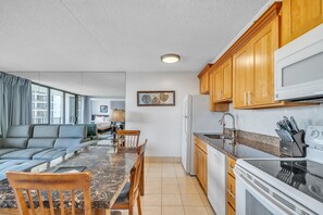 A modern kitchen with wooden cabinets, a built-in microwave, and a granite countertop. - Excellent Diamond Head View Condo - Remodeled, Free Parking! (Honolulu)