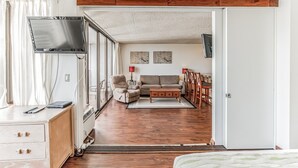 Une pièce comprenant un lit, un bureau avec un ordinateur, une télévision, un canapé et une table à manger avec des chaises.