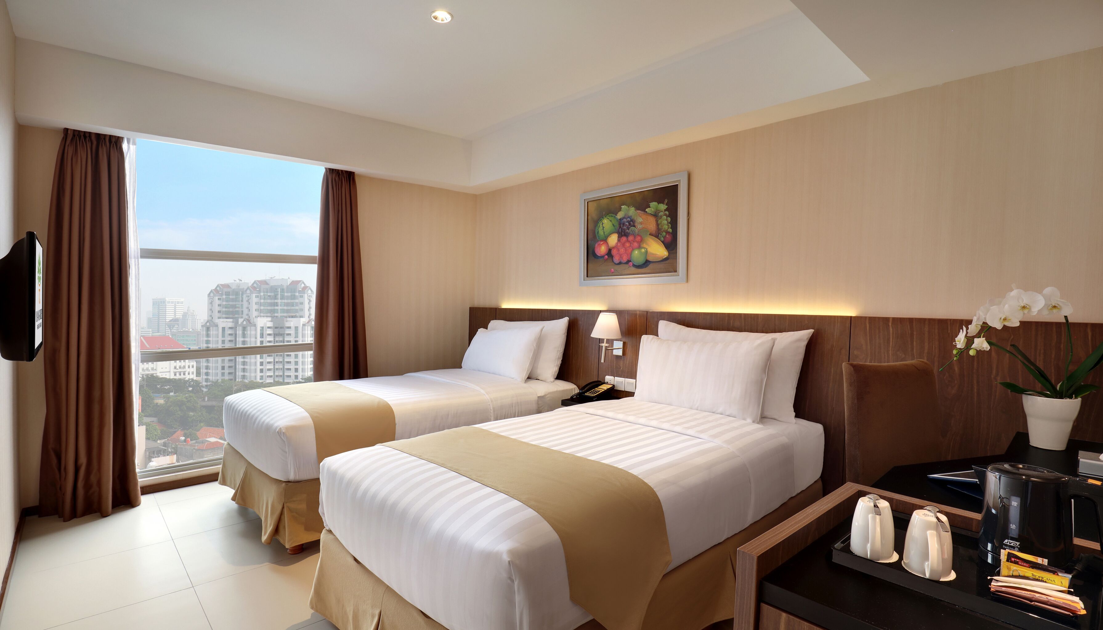 A hotel room with two beds, a desk with a coffee maker, a phone, and a painting on the wall.