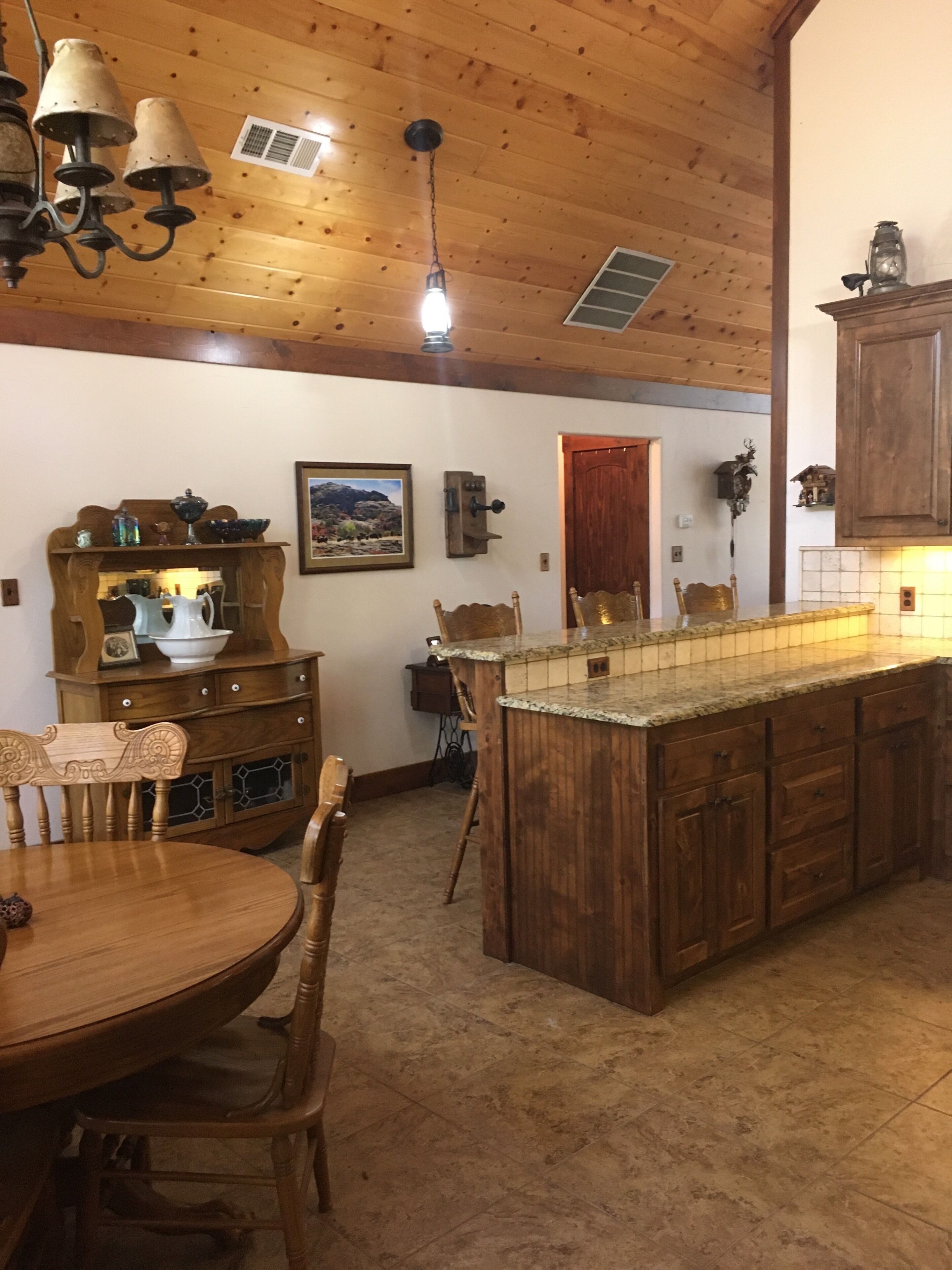Un intérieur en bois comprenant une table à manger, des chaises, un îlot de cuisine et un luminaire suspendu.