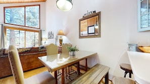 A dining area with a glass table, wooden chairs, a bench, and a small potted plant. - Woodlands #25 3 Bedroom Condo (Mammoth Lakes)