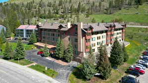 A multi-story hotel with a parking lot and a mountainous backdrop.
