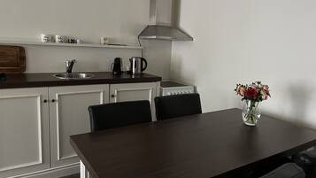 Een moderne keuken met witte kastjes, een donker houten tafel en een bloevas.
