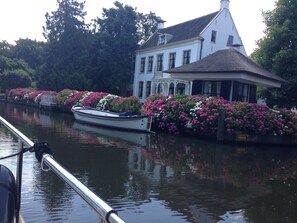 Un canal bordé de bâtiments ornés de jardinières et sur lequel est amarré un bateau.