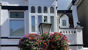 Un edificio blanco con un amplio ventanal y un jardín de flores al frente.