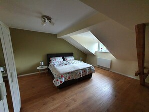 A bedroom with a bed, a nightstand, a window, and a sloped ceiling.