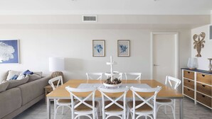 A dining area with a wooden table, white chairs, and a white cabinet with baskets.