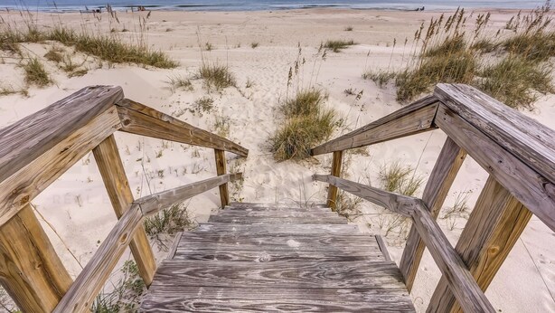 A wooden staircase leading to a beach with sand dunes and a clear view of the ocean. - South Fletcher Beachfront Home by RedAwning (Fernandina Beach)