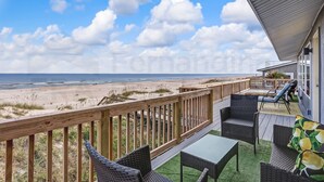 A wooden deck with outdoor furniture overlooking a beach. - South Fletcher Beachfront Home by RedAwning (Fernandina Beach)