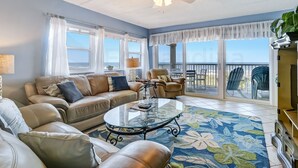 A living room with a glass coffee table, leather sofas, and a view to the outside. - Updated Condo Featuring Fresh Atlantic Breeze by RedAwning (Fernandina Beach)