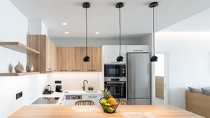 Eine moderne Küche mit Holzschränken, einem Edelstahlkühlschrank und einem Essbereich mit Holztisch und Stühlen.