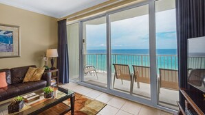 A living room with a sofa, coffee table, and a view of the ocean through large sliding glass doors. - 🏖️Beachfront, Fab Views-1BR+Bunk Boardwalk 805🏖️ (Panama City Beach)