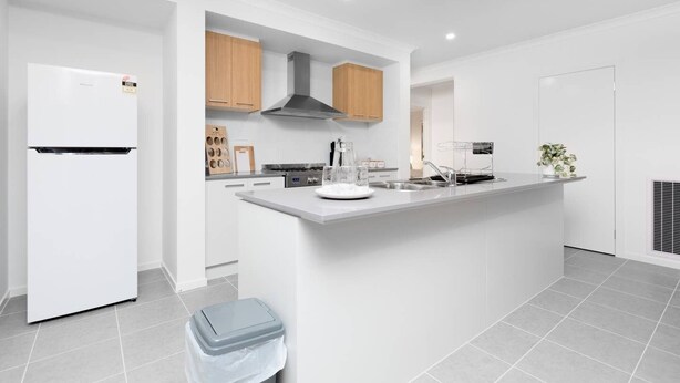 A modern kitchen with white cabinetry, a central island, and a built-in oven. - Resortstyle 4BR House With Parking@werribee (Werribee)