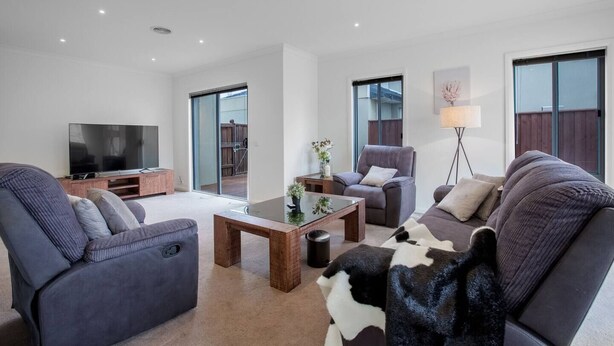 A modern living room with a flat-screen TV, two sofas, a coffee table, and a floor lamp. - Superb Luxe 5BR House@point Cook Near Lake (Point Cook)