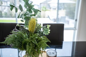 A room with a large window, a plant arrangement, and a glass candle holder. - Superb Luxe 5BR House@point Cook Near Lake (Point Cook)