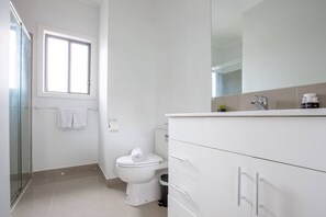 A modern bathroom with a toilet, a shower, and a vanity with a mirror. - Stunning 3beds Near Knox Shopping Centro@wantirna (Wantirna South)