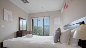 Quarto de hotel com uma cama grande, uma mesa de cabeceira, janela com vista e obras de arte nas paredes.