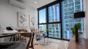 A modern living room with a large window, a dining area, and a flat-screen TV. - Cozy APT With City Views Next to Meblourne Central (Melbourne)