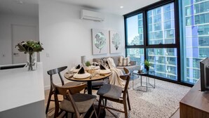 A modern living room with a dining area, large windows, and a city view. - Cozy APT With City Views Next to Meblourne Central (Melbourne)