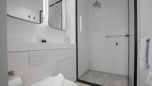A modern bathroom with a glass-enclosed shower, a white sink, and a toilet. - Cozy APT With City Views Next to Meblourne Central (Melbourne)