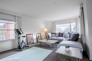 A modern living room with a grey sofa, a coffee table, an exercise bike, and two framed movie posters.